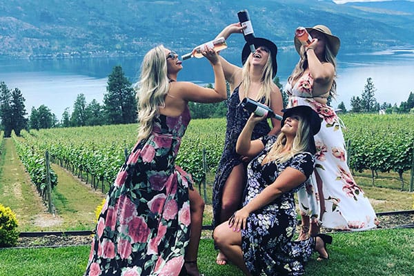 Ladies drinking wine in a Lake Country vineyard on a wine tour