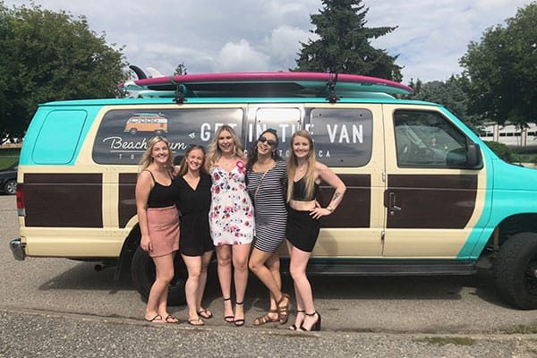 Ladies on a wine tour in Kelowna posing with the Beach Bum Tours van
