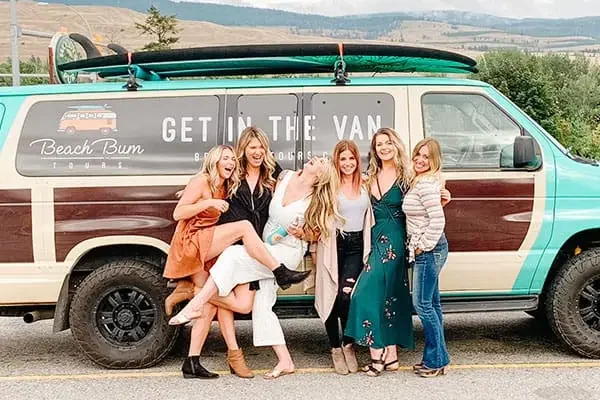 Girls on a Kelowna wine tour posing with the Beach Bum Tours van